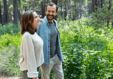 Man and woman smiling and walking through greenery